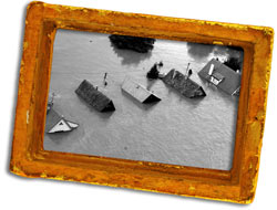 Black and white photograph of rooftops in a flooded area. 