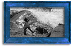 Black and white photograph of a young girl on the ocean shore with waves crashing.