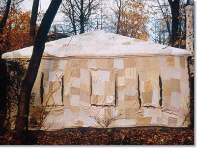 "Cozy": a house sewn together with fabric, in a woods setting