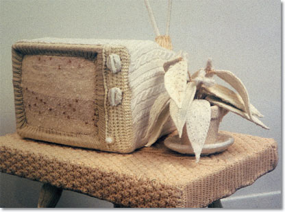 Photo of a TV, covered in knitted wool.